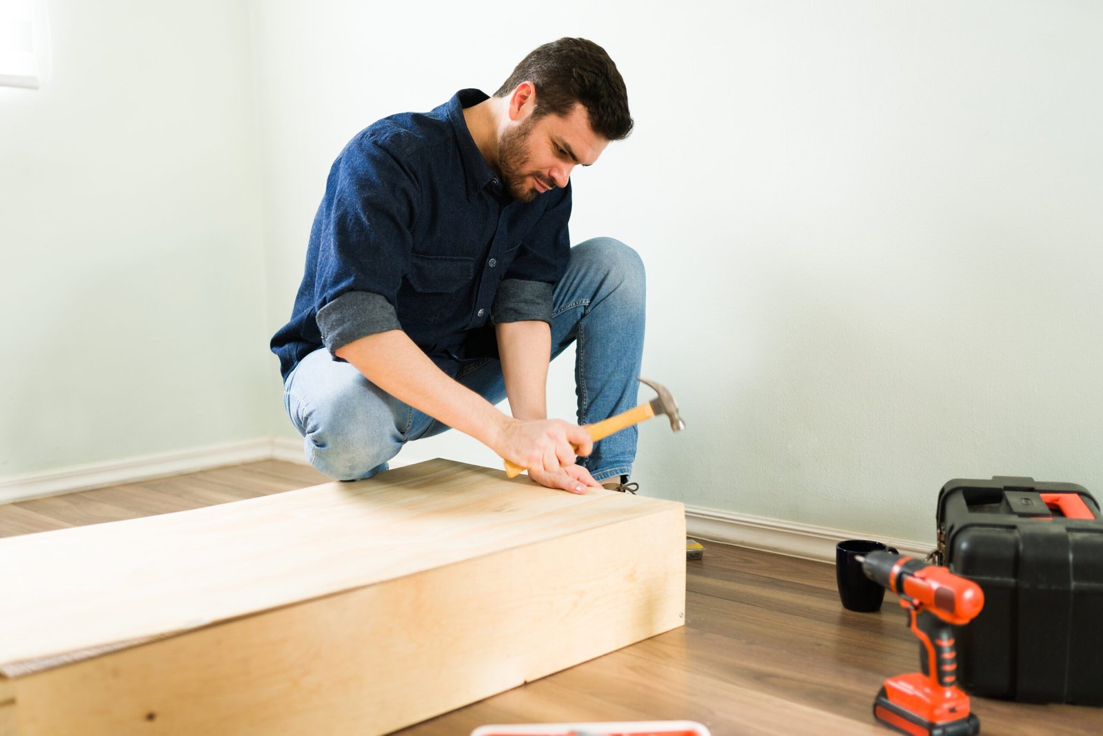 good looking young man building himself new wooden shelf doing some diy home renovations