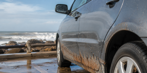 Veículo estacionado próximo ao litoral com sinais de corrosão na parte inferior da carroceria, ilustrando os efeitos da maresia na lataria e a importância da prevenção contra a corrosão automotiva.