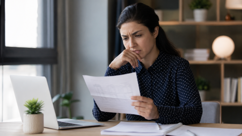 Servidora pública analisando o contracheque em um escritório, verificando documentos e possíveis inconsistências na remuneração, em ambiente profissional e organizado.